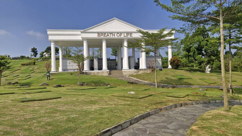 Bangunan megah Rumah Abu Breath of Life di San Diego Hills dengan pilar-pilar putih, area hijau, dan taman pemakaman yang tertata rapi.