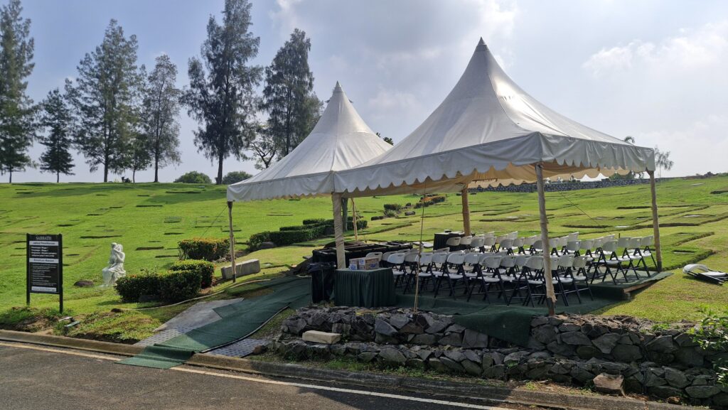 Fasilitas paket pemakaman standar San Diego Hills dengan tenda putih, kursi tamu, dan perlengkapan prosesi pemakaman di area taman hijau.
