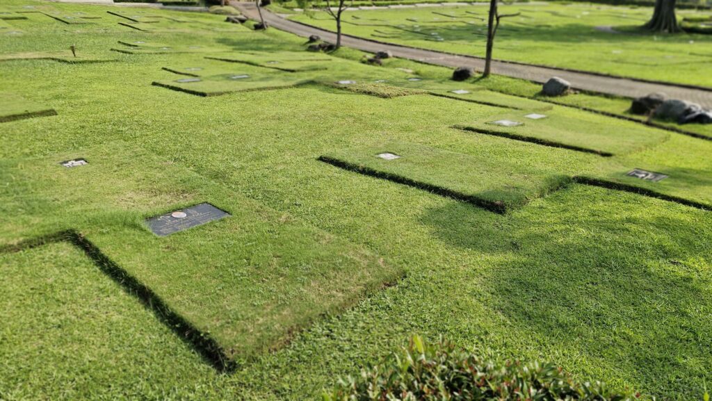Area lahan makam tipe Single di San Diego Hills dengan nisan datar berlapis rumput hijau terawat di tengah taman yang asri dan damai.
